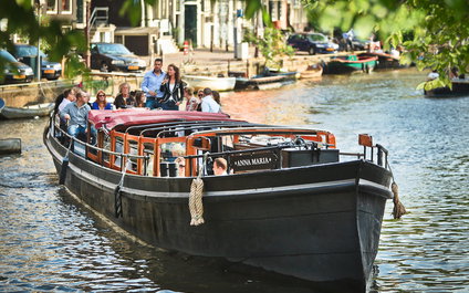 Open boot met gasten onder een zonnekap op een Amsterdamse gracht